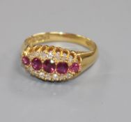 An early 20th century 18ct gold, five stone ruby elliptical shaped ring with diamond set border,