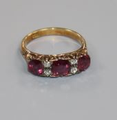 An early 20th century 18ct gold, three stone ruby and four stone diamond ring, size L.