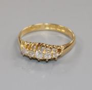 An early 20th century 18ct gold and graduated five stone diamond half hoop ring, size M.