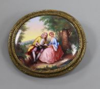 A gilt metal mounted mother of pearl oval panel, painted with lady and gentleman in woodland