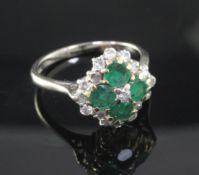 An 18ct white and yellow gold, emerald and diamond cluster ring, claw set with four emeralds and