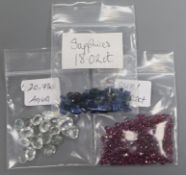Three small bags of loose cut sapphires, aquamarines and rubies.