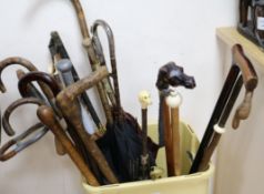 A collection of assorted walking sticks and parasols and a bayonet