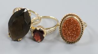 A 9ct gold smoky quartz cocktail ring, a 9ct goldstone ring and a 14ct gold and garnet ring (3)