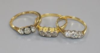 Three assorted 18ct gold and three stone diamond rings including one illusion set.