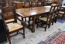 A 17th century style oak draw leaf dining table with a set of ten rush seat chairs including two