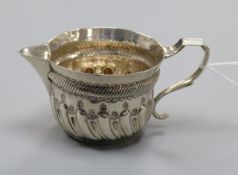 A late Victorian silver embossed cream jug, London 1885,