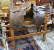 A Victorian saddle stand with two leather saddles W.148cm