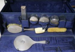A George V travelling toilet set, with eight assorted silver mounted items and two lids, in a blue