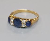 An early-mid 20th century yellow metal, seven stone sapphire and diamond half hoop ring, size N.