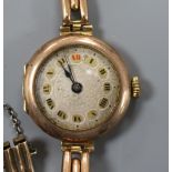 A lady's early 20th century 9ct. gold manual wind wrist watch on a 9ct gold bracelet.