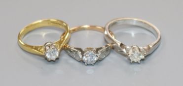Three assorted 18ct gold and solitaire diamond rings including one set in white gold.