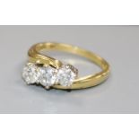 An 18ct gold and three stone diamond crossover ring, size N/O.