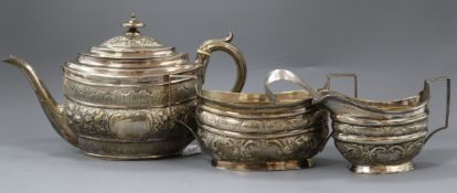 A matched George III silver embossed three piece tea set, London, 1802 and later, teapot by Urquhart