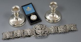 A pair of silver mounted dwarf candlesticks, a pierced plated belt and a silver fob watch.