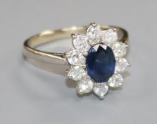 A modern 18ct white gold, sapphire and diamond oval flower head cluster ring, size R/S.