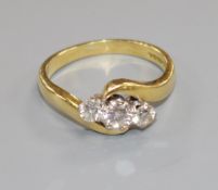 A modern 18ct gold and three stone diamond crossover ring, size Q.