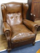 A pair of brown leather upholstered wing armchairs