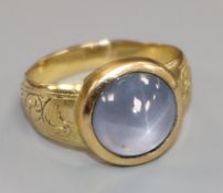 An engraved yellow metal and cabochon star sapphire ring, size O.