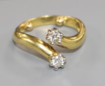 A yellow metal and two stone diamond crossover ring, size K/L.