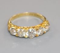 A late Victorian yellow metal and graduated five stone diamond half hoop ring, size J.