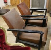 A pair of ebonised, tan leather reclining armchairs