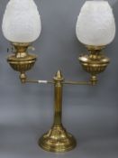 A Victorian brass two light oil lamp, on column support and circular domed base supporting two