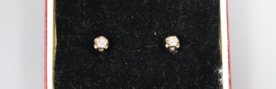 A pair of white metal and solitaire diamond ear studs.