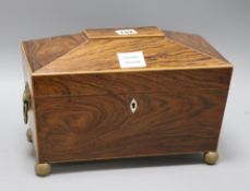A Regency rosewood sarcophagus shaped tea caddy, the lifting top enclosing two covered compartments,