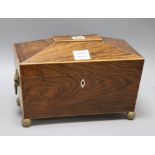 A Regency rosewood sarcophagus shaped tea caddy, the lifting top enclosing two covered compartments,