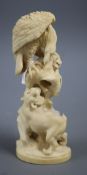 A Japanese Meiji ivory okimono, carved with a tiger and an eagle attacking a monkey on a tree stump,