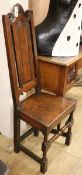 A mid 17th century oak chair, with panelled high back and scroll cresting, solid seat on turned