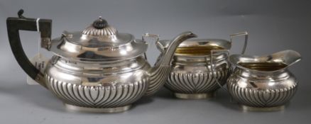 A matched three-piece silver tea service, of oval half-fluted form, comprising a teapot with