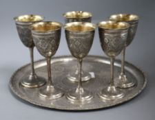 A set of six Persian engraved white metal goblets and a tray, tray 30cm.