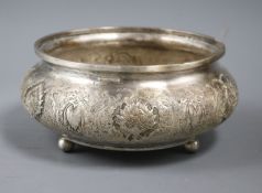 A Persian embossed white metal bowl, on three bun feet, 17.5cm.