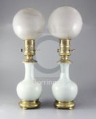 A pair of mid 19th century French ormolu mounted celadon porcelain oil lamps, with opaque circular