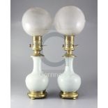 A pair of mid 19th century French ormolu mounted celadon porcelain oil lamps, with opaque circular