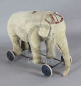 A Steiff pale gold plush pull along elephant, with spoke wheels, button to ear, length 29in.