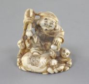 An ivory netsuke of Daikoku and two boys, Meiji period, Daikoku holding his mallet, with his foot