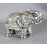A large Indian white metal overlaid hardwood model of an elephant, standing with raised trunk,