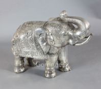 A large Indian white metal overlaid hardwood model of an elephant, standing with raised trunk,