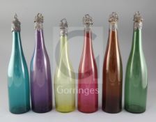 Six assorted coloured glass wine bottles with vineous collars and stoppers, including five with