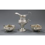 A George III silver cream jug with later embossed decoration and a pair of silver salts.