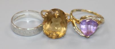 A 9ct gold and citrine dress ring, a 9ct white gold band and a yellow metal and amethyst ring.