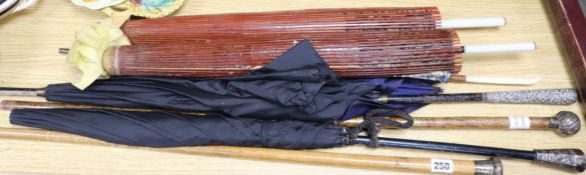 A collection of parasols and canes, some silver mounted