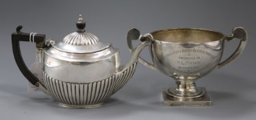 An Edwardain demi-fluted silver teapot and a later two handled silver trophy cup, gross 22 oz.