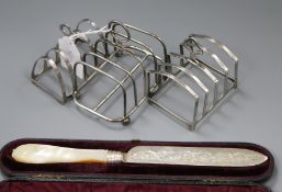 Three silver toastracks and cased Victorian silver and mother of pearl handled knife.