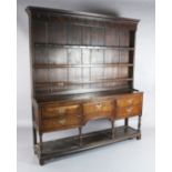 A George III oak dresser, with three shelf rack and five long drawers over a pot board, W.6ft 3in.