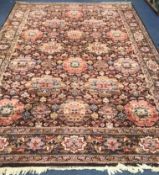A Persian-style aubergine ground carpet, all over woven with large stylised flowerheads, 350 x 249cm