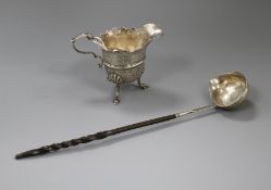 A Georgian Irish silver cream jug (a.f.) and a white metal toddy ladle.
